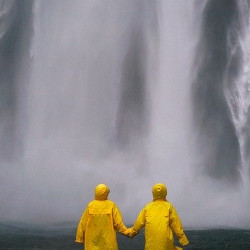 Couple main dans la main face à une chute d'eau